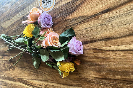 Colorful flowers, with long stems laying on a bamboo floor.