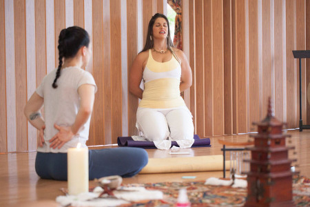 Jenna Lomazzo in a yoga pose with a student.
